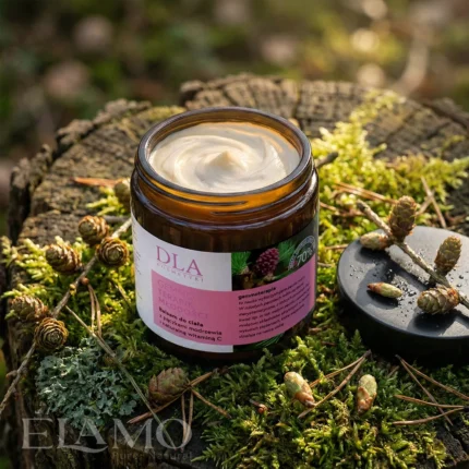 Otwarty słoiczek balsamu Gemmoterapik Młodości na mchu w otoczeniu świeżych pączków modrzewia.