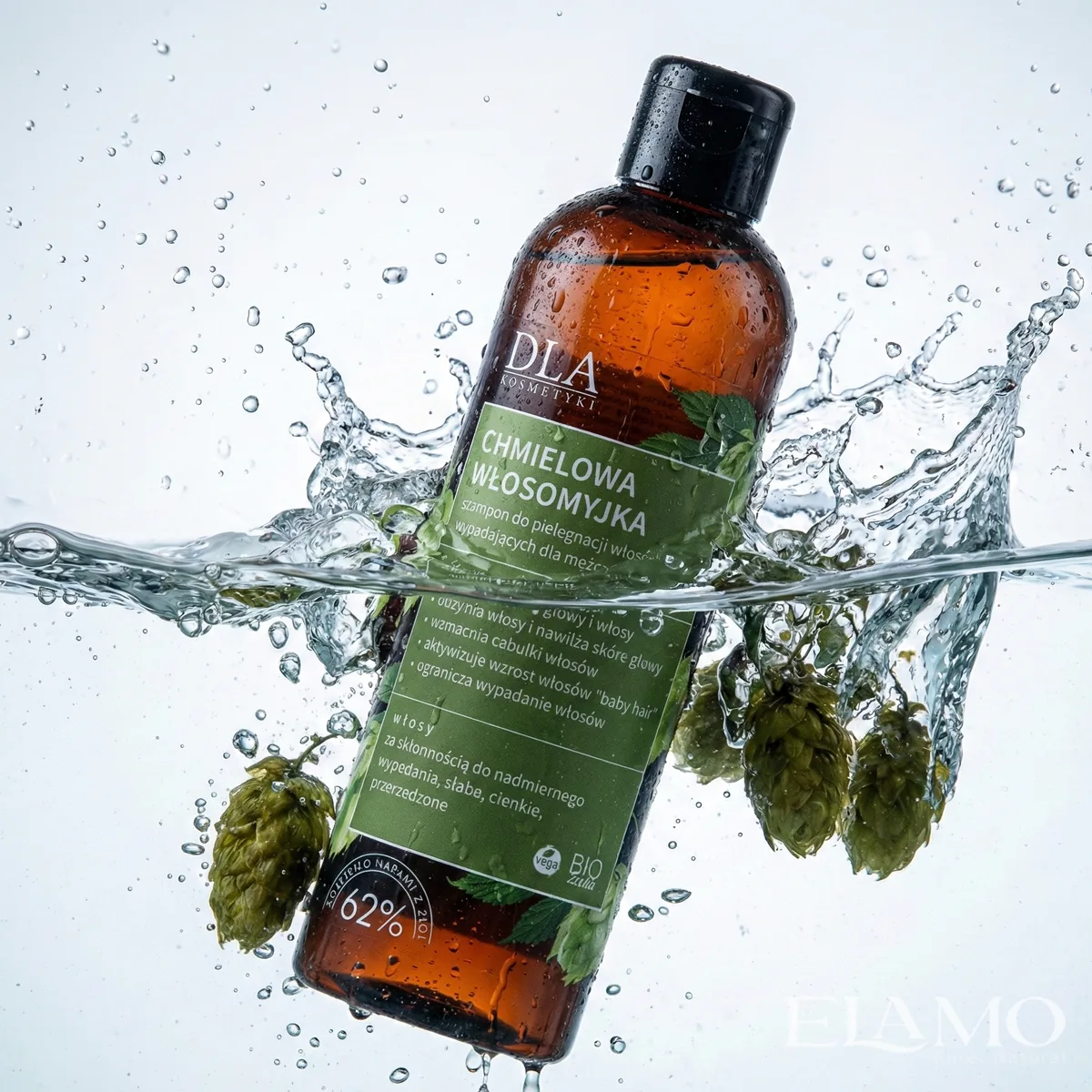 Dynamiczne ujęcie szamponu Chmielowa Włosomyjka wpadającego do wody ze świeżym chmielem.