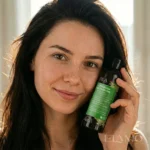 Uśmiechnięta kobieta trzymająca przy twarzy szampon Koperkowa Włosomyjka