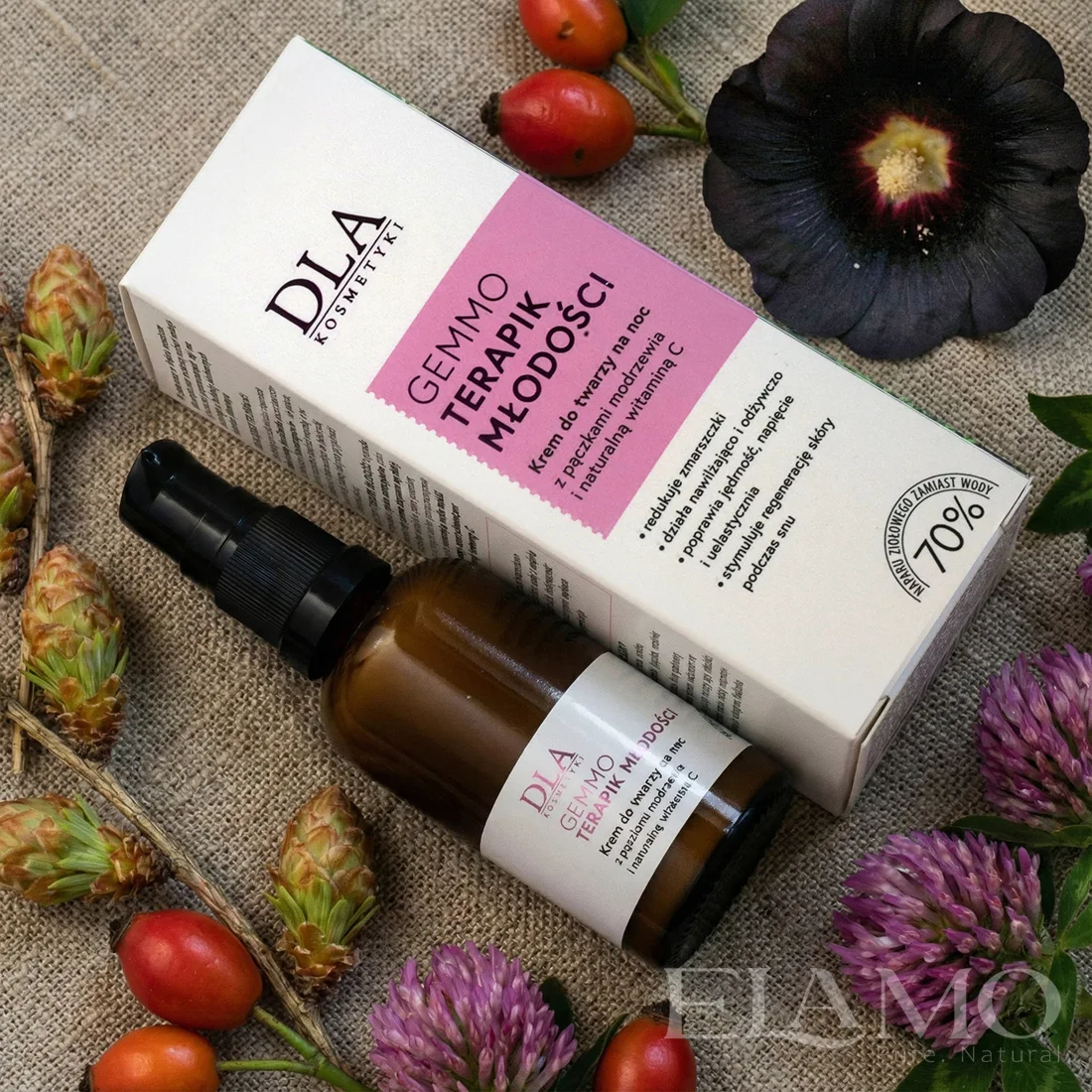 Krem Gemmoterapik Młodości leżący na lnie w otoczeniu pączków modrzewia i kwiatów koniczyny.