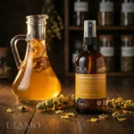 Dziewannowy Ziołoocet marki DLA stojący na drewnianym stole obok karafki z octem i suszonych ziół.