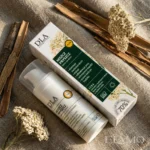 Niszcz Pryszcz krem na dzień – flatlay: butelka i kartonik na tkaninie, motyw krwawnika i kory wierzby, 70% naparu