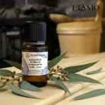 Duży olejek eteryczny Eukaliptus Globulus 15ml Florihana na ławie w saunie, w tle piec z kamieniami; klasyczny zapach do inhalacji.