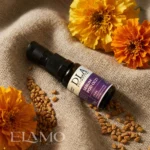 Ciemna szklana butelka serum leżąca na lnie wśród kwiatów nagietka