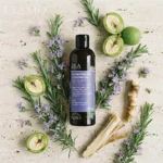 Artystyczna kompozycja flatlay szamponu Rozmarynowa Włosomyjka otoczonego gałązkami rozmarynu i przekrojonymi orzechami na kamiennym tle.