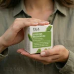 Kobieta w zielonej koszuli trzymająca w dłoniach opakowanie szamponu Sosnowa Włosomyjka.