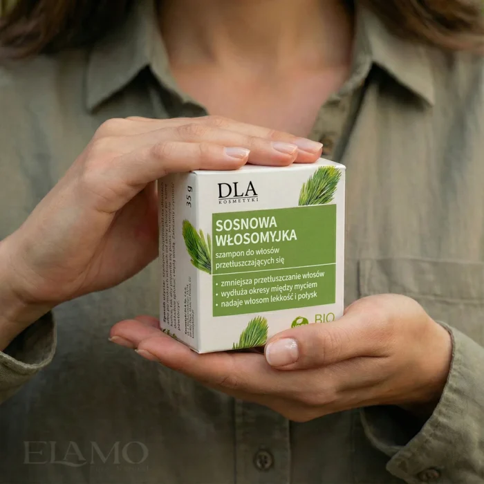 Kobieta w zielonej koszuli trzymająca w dłoniach opakowanie szamponu Sosnowa Włosomyjka.