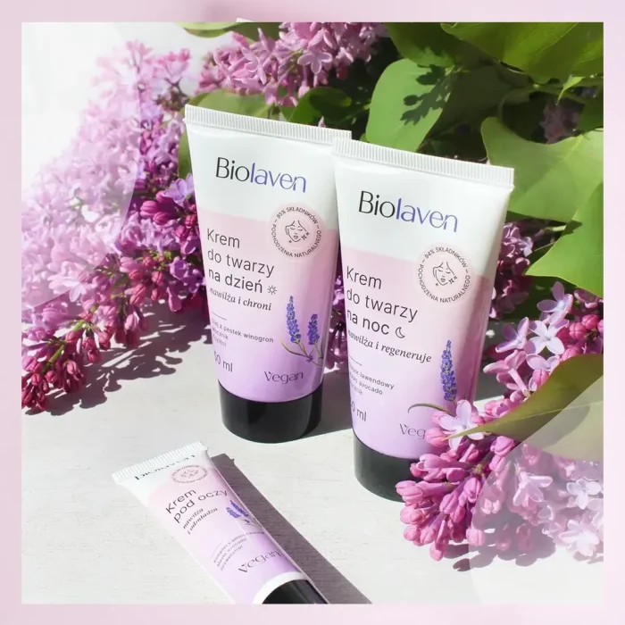 Wegańskie kremy do twarzy BiolaVen na dzień i na noc oraz krem pod oczy, prezentowane na tle różowych kwiatów bzu. Produkty z olejem z pestek winogron, umieszczone na jasnym, drewnianym tle w słoneczny dzień. Naturalna pielęgnacja skóry, polska marka kosmetyczna, vegan friendly.