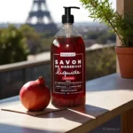 Naturalne mydło marsylskie owoc granatu w płynie Bômance 1L – butelka mydła w słonecznym świetle, ustawiona na balkonie z widokiem na wieżę Eiffla, obok granat, naturalna pielęgnacja na bazie 98% składników pochodzenia naturalnego