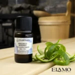 Olejek bergamotowy BIO Florihana w butelce 10 ml na tle drewnianej ławeczki sauny z aromatyczną skórką bergamotki