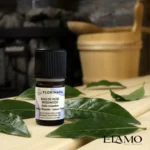 Organiczny olejek eteryczny Florihana z drzewa różanego stojący na drewnianej ławie w saunie, w tle kamienie i ceber.