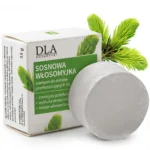 Szara kostka szamponu Sosnowa Włosomyjka leżąca obok biało-zielonego opakowania.