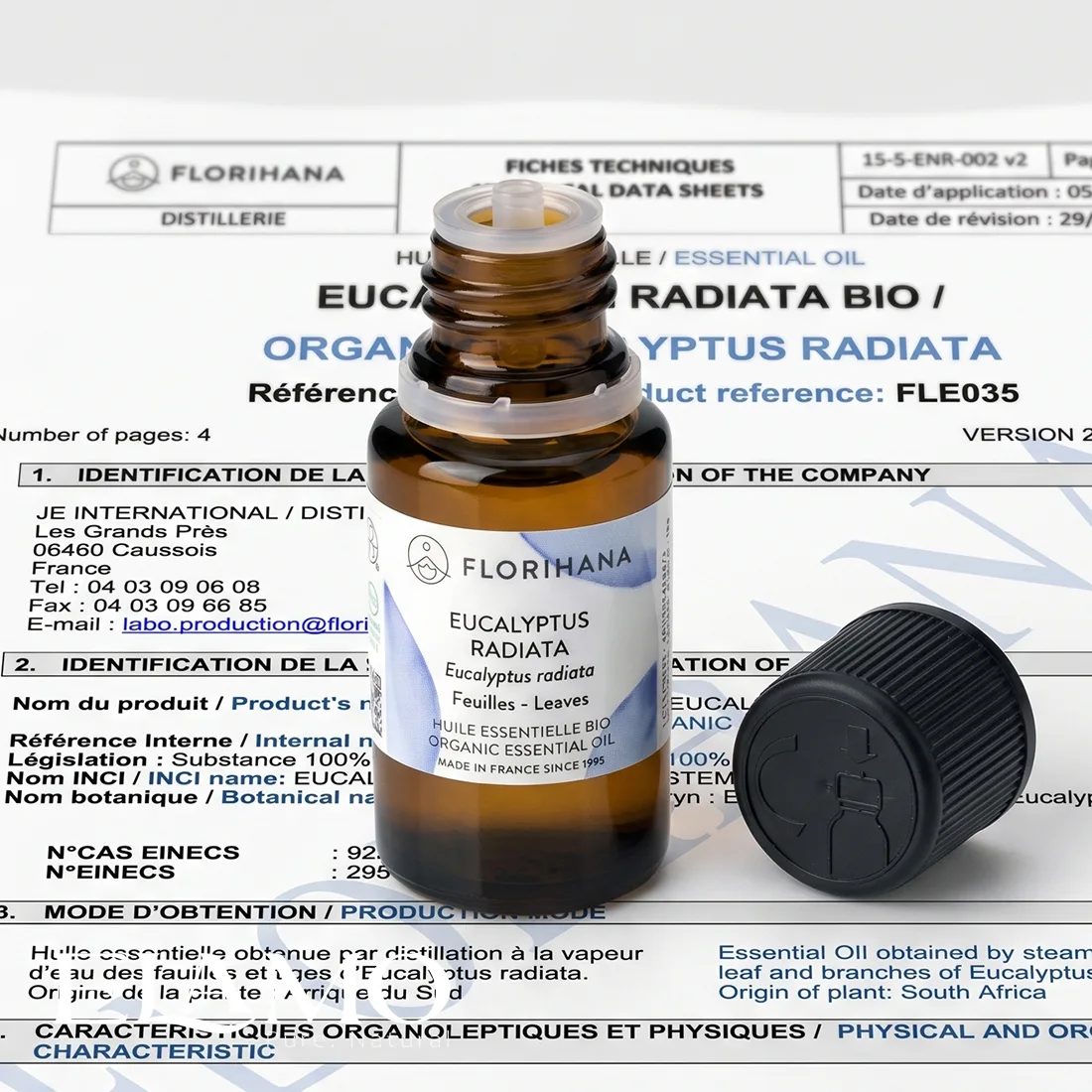 Otwarta buteleczka olejku Eucalyptus radiata z widocznym kroplomierzem na tle dokumentacji technicznej i raportów laboratoryjnych